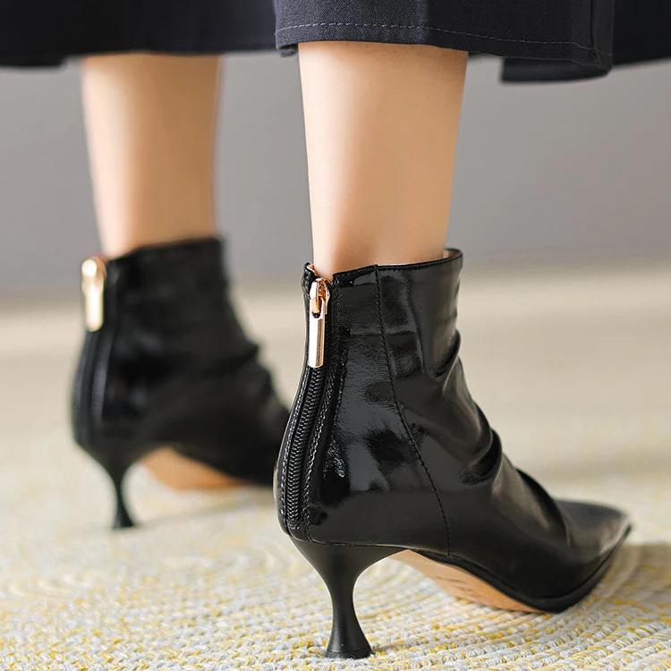 Woman wearing kitten keel ankle boots in black shiny leather