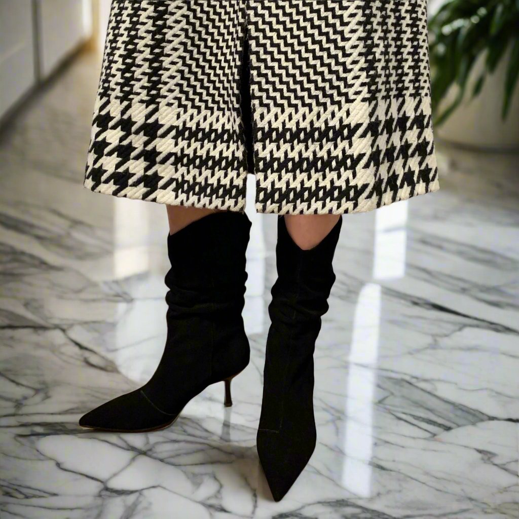 Woman wearing black and white coat and matching black suede high heel boots