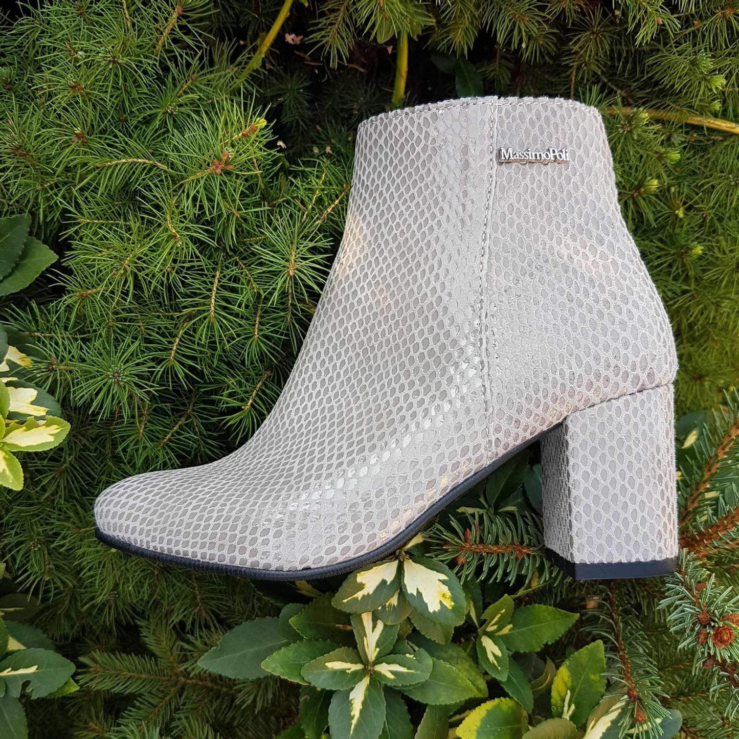 Grey leather ankle boots set against greet foliage 