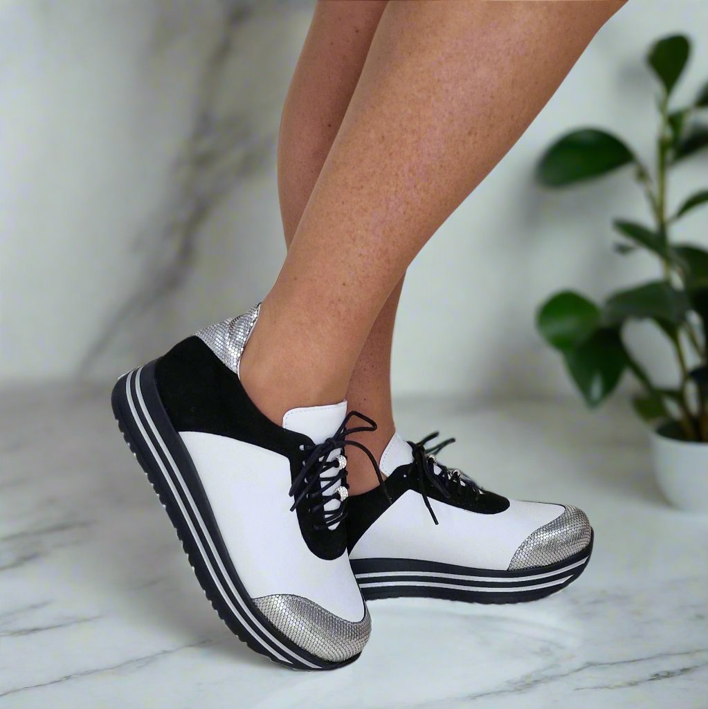 Woman wearing petite sneakers in white silver and black leather