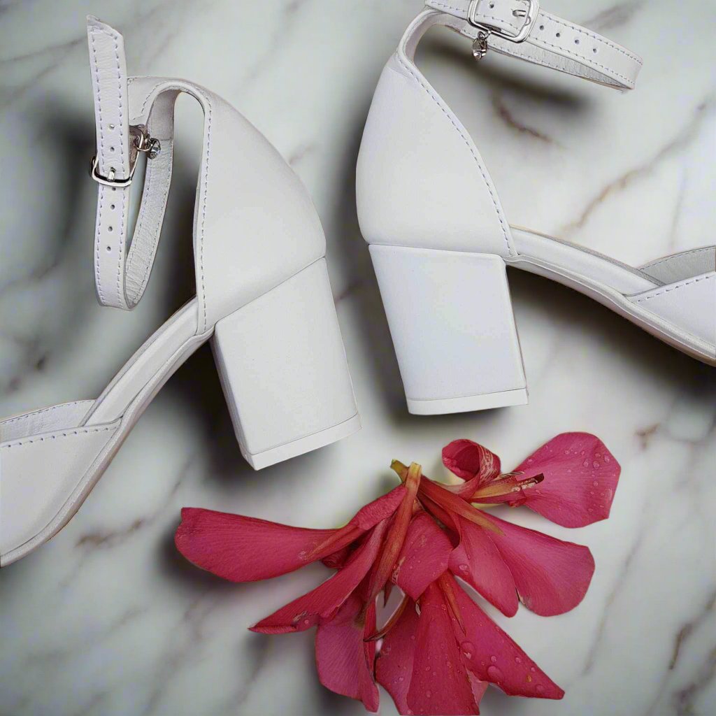 White petite wedding heels lying on a marble floor