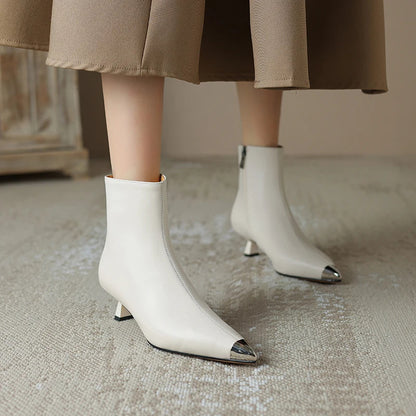 Woman wearing pointed toe ankle boots in white leather