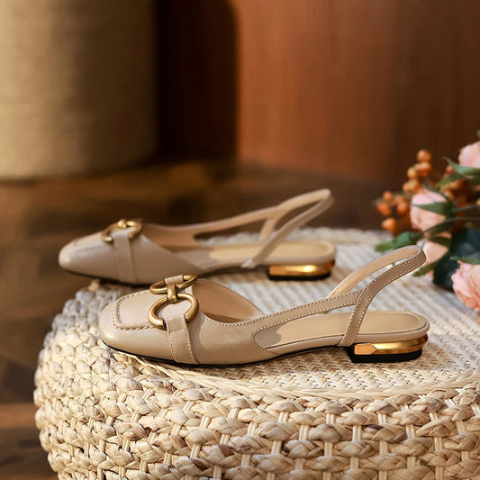 A pair of beige leather slingback shoes sat on a whicker poof 