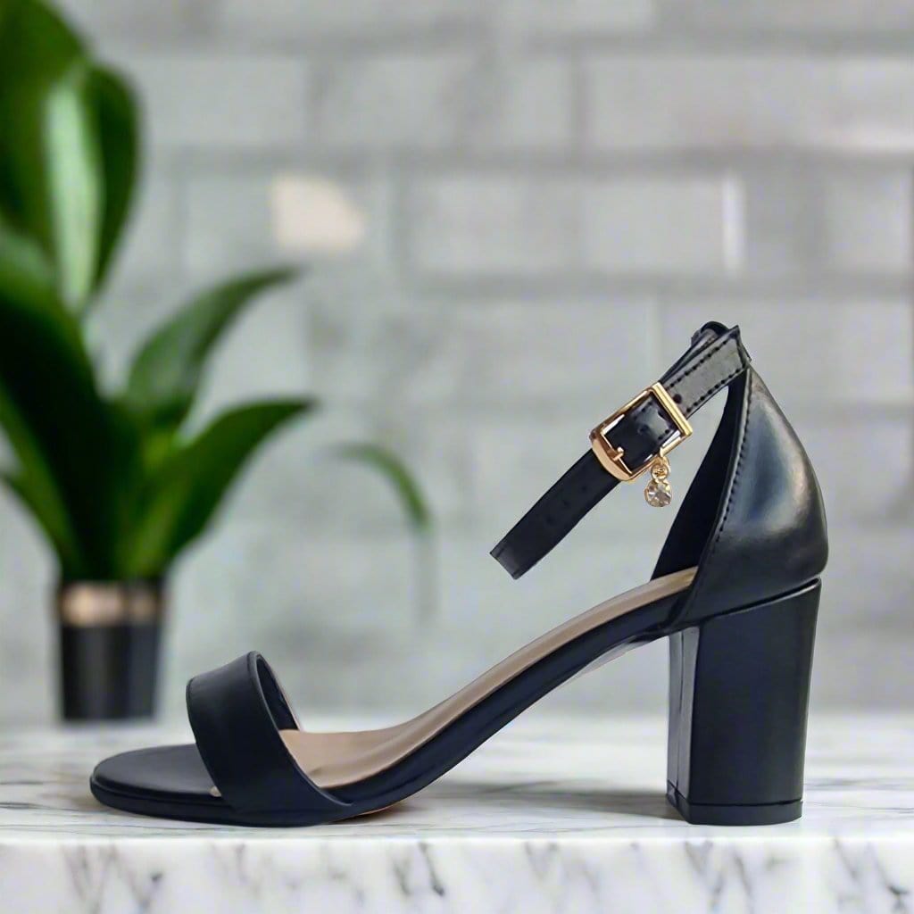 Block heel sandals with a gold buckle on a stand