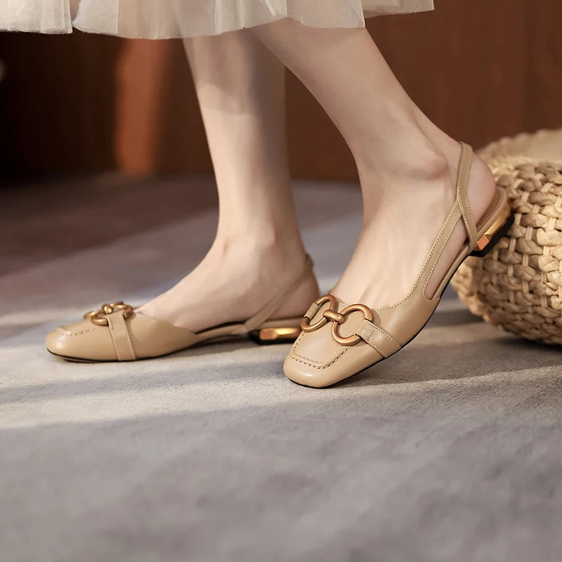 A woman wearing beige leather flat sandals