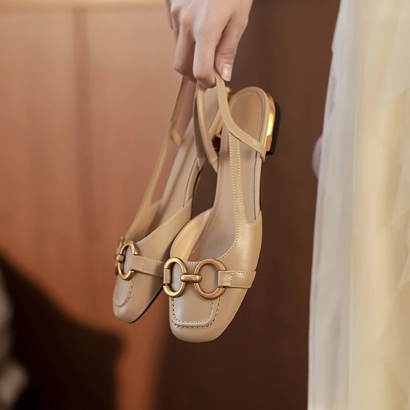 a woman holding nude leather small size open heel sandals 