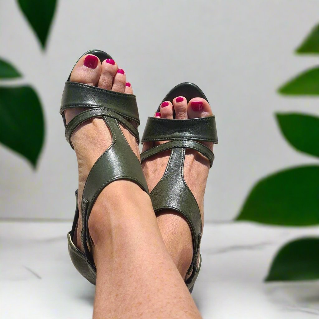 Woman wearing green leather strap sandals. 