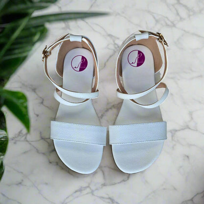 White leather cross strap sandals with a gold buckle