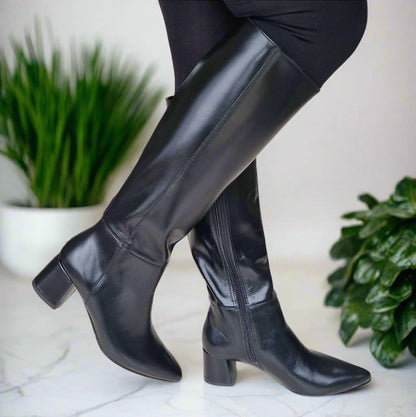 Woman wearing petite black leather knee high boots set on a block heel 