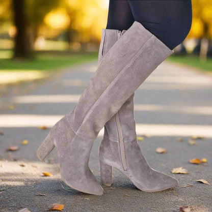 Woman wearing beige suede knee high boots and black leggins