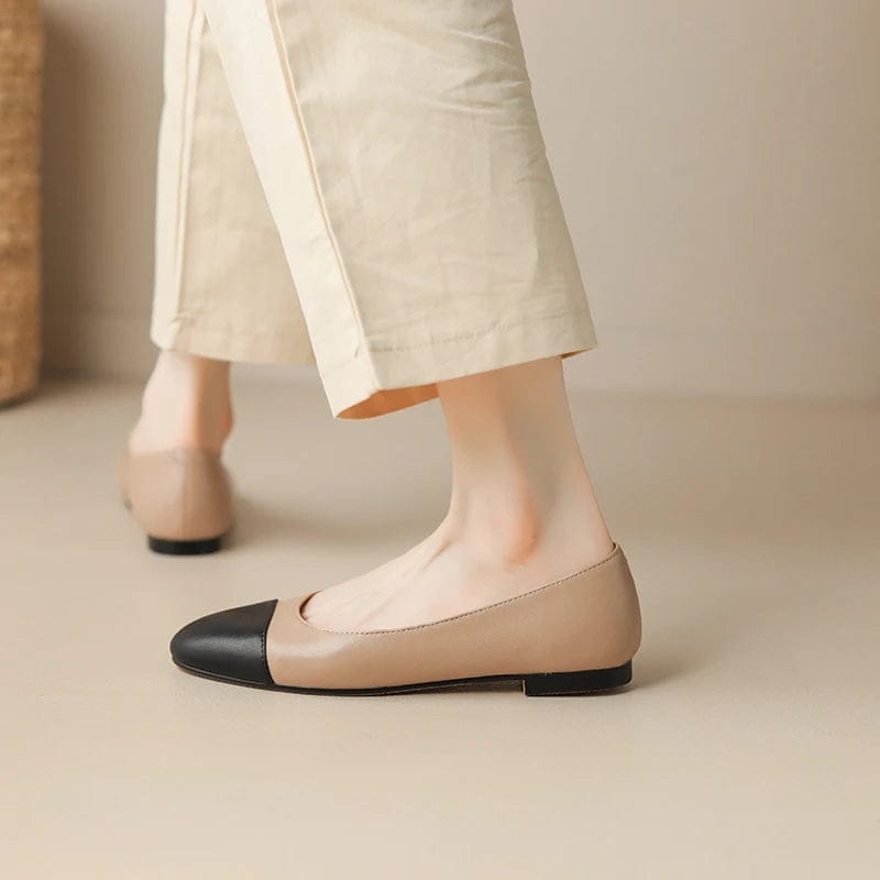 Woman wearing cream trousers and beige and black round toe ballerina shoes