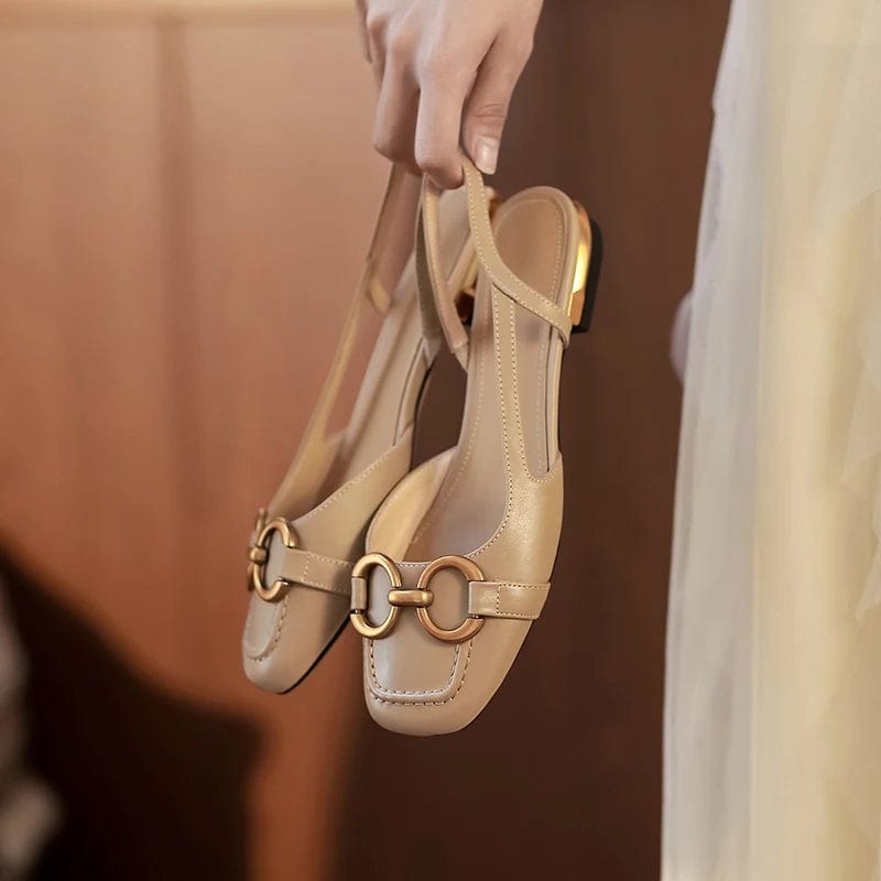 Woman holding beige leather ballerina shoes