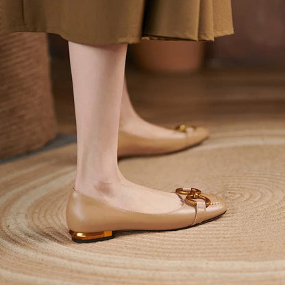 Woman wearing a beige skirt and matching beige leather ballerina style shoes with gold buckle