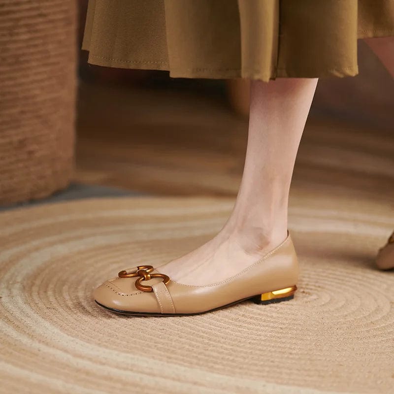 Woman wearing beige leather ballerina pumps with gold heel and buckle