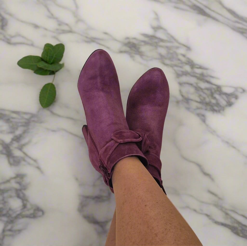 A woman wearing burgundy suede ankle boots